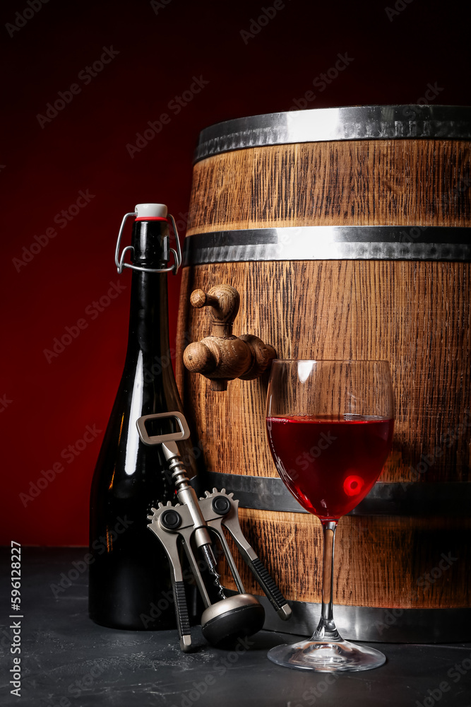 Wooden barrel, corkscrew, bottle and glass of wine on dark background