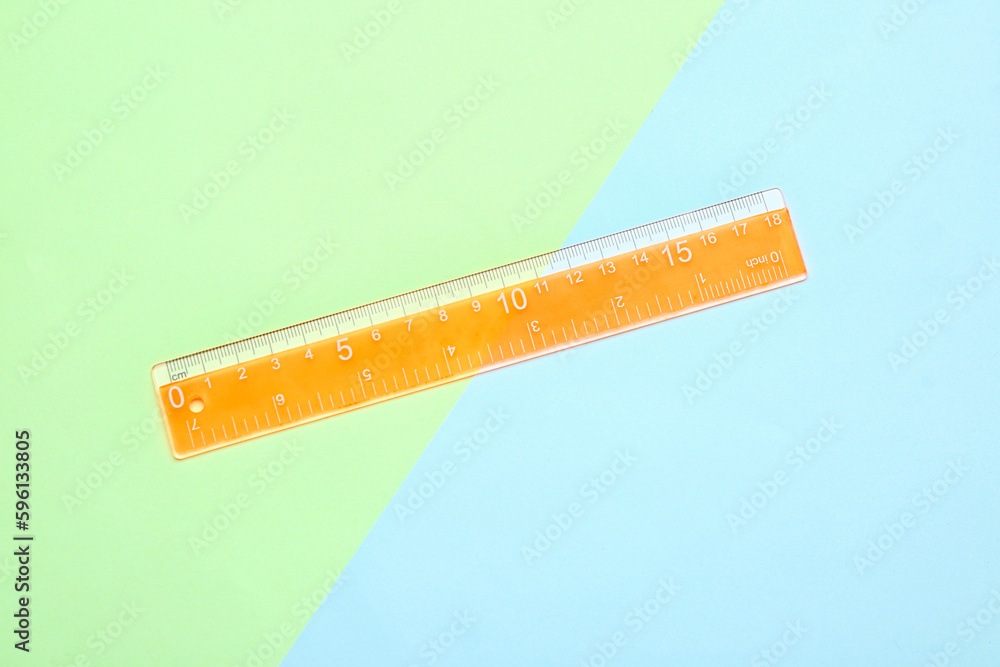 Orange plastic ruler on color background