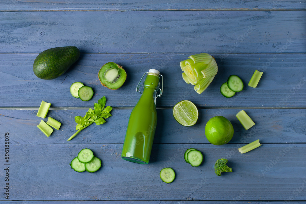 Glass of tasty green juice on blue wooden background