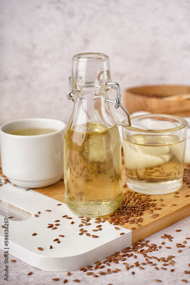 Bottle, glasses with flax oil and seeds on light background