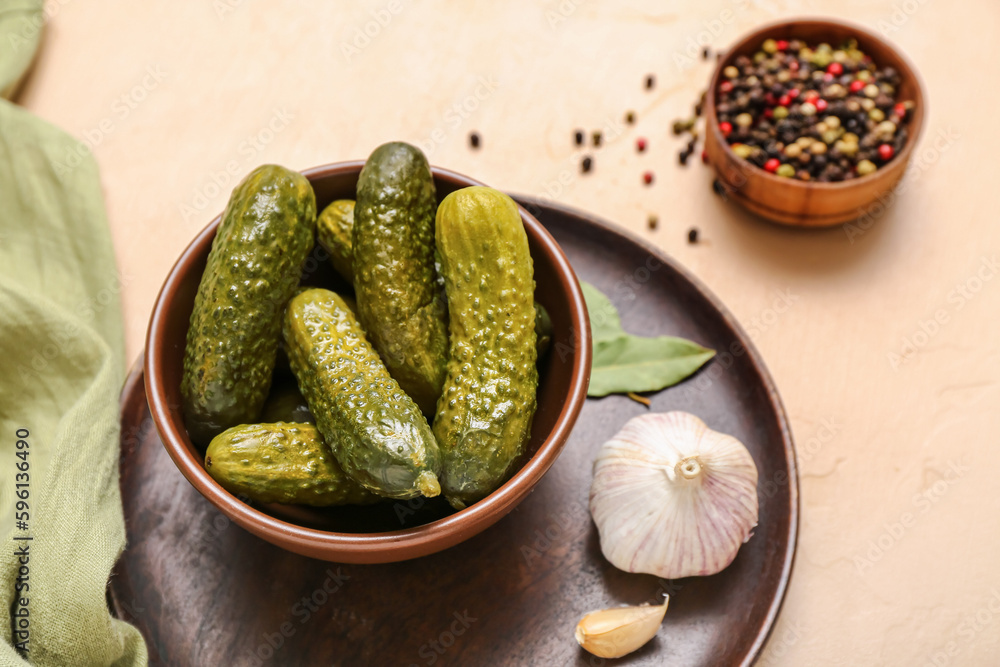 Bowl with tasty fermented cucumbers on beige background