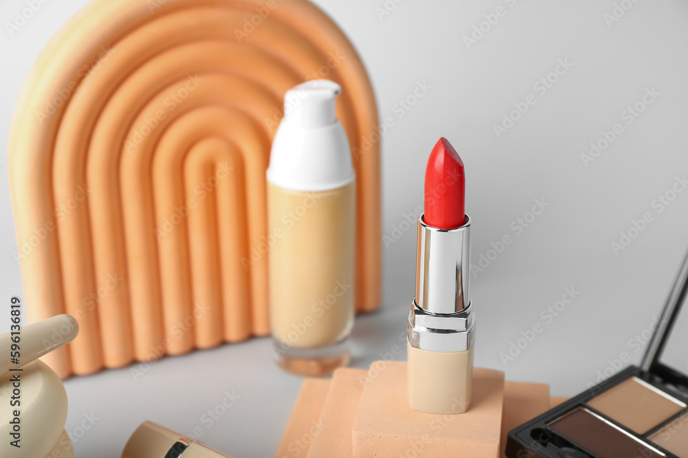 Decorative plaster podiums and cosmetics on grey background