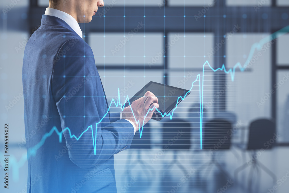 Close up of businessman hand pointing at tablet with growing blue financial forex chart on blurry of