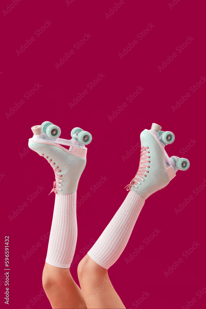 Legs of young woman in roller skates on pink background