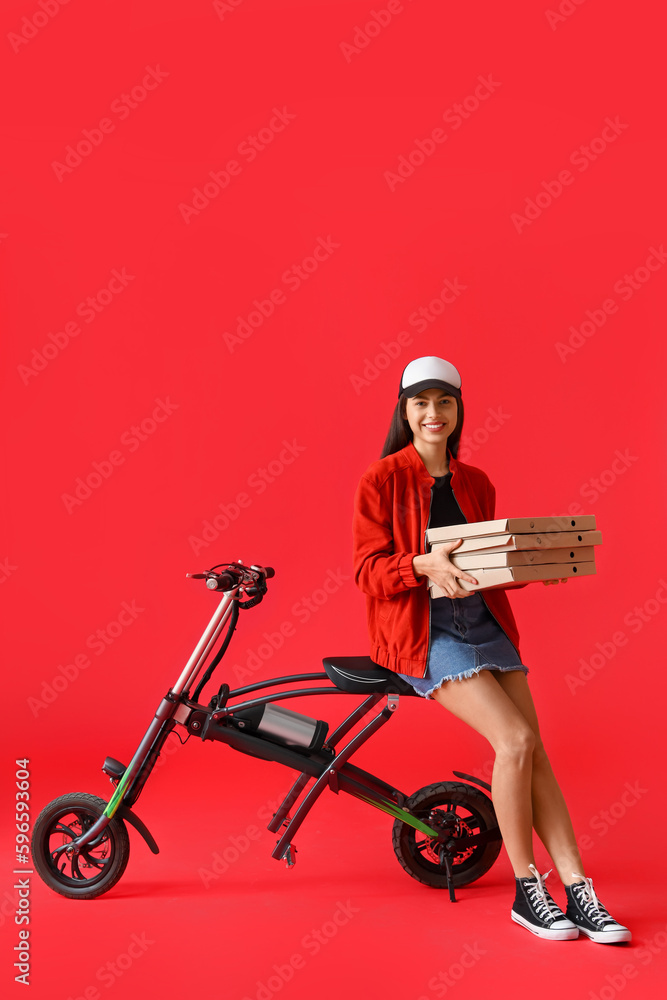 Young woman with boxes of tasty pizza and electric bike on red background