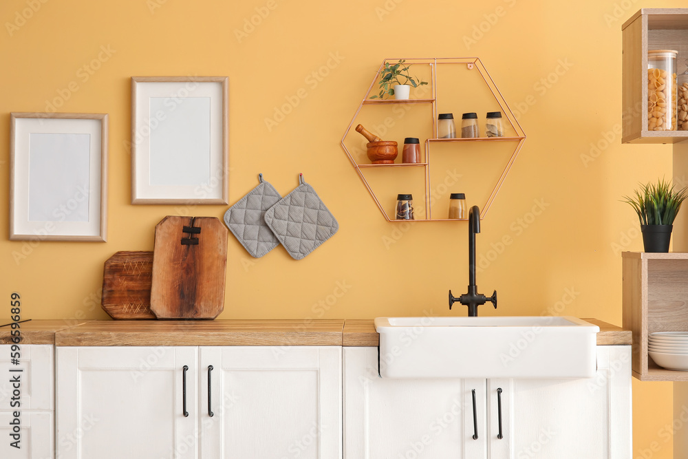 Kitchen counters with sink and wooden boards near yellow wall