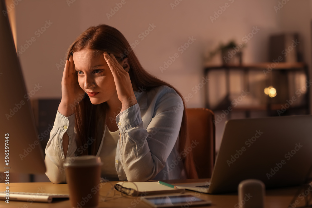 Tired female programmer working with computer in office at night