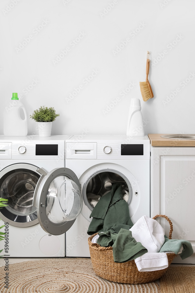 Modern washing machines with dirty clothes in laundry room