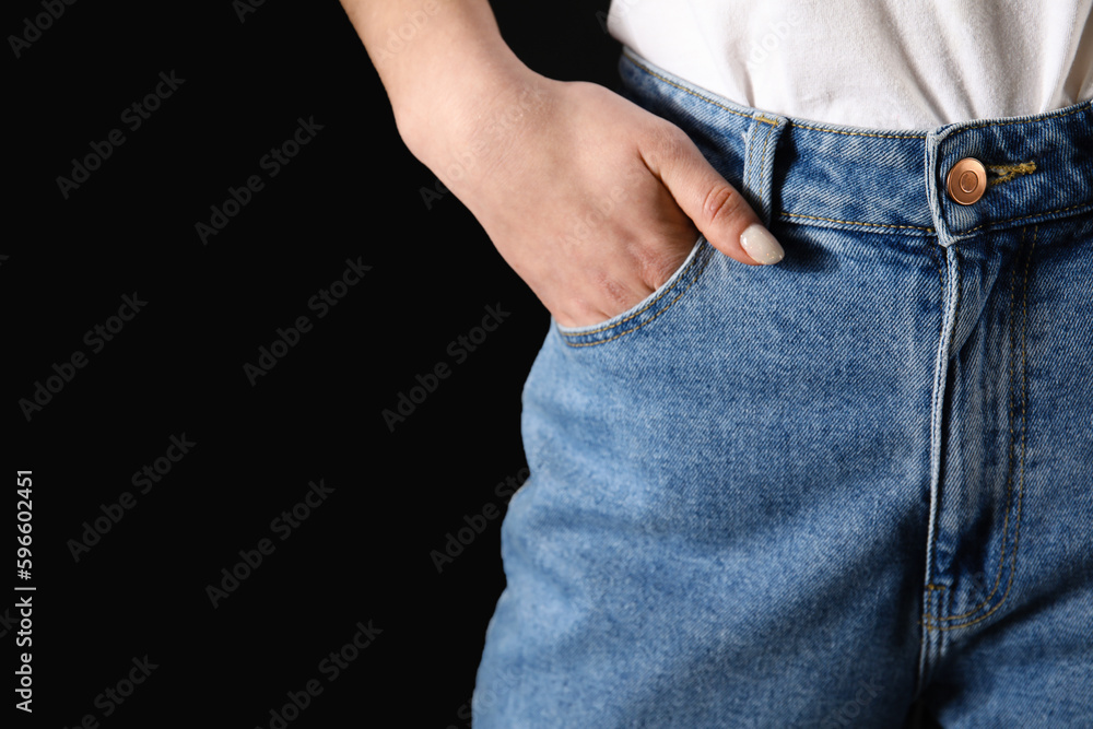 Young woman in stylish jeans on black background, closeup