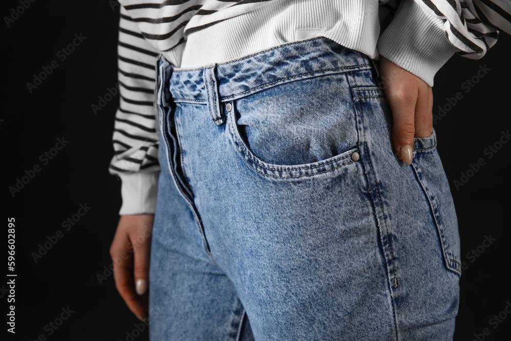 Young woman in stylish jeans on black background, closeup