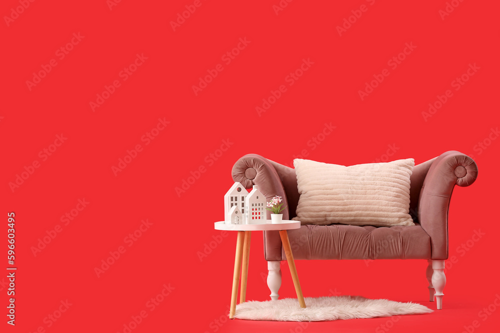 Cozy sofa with cushion and coffee table on red background