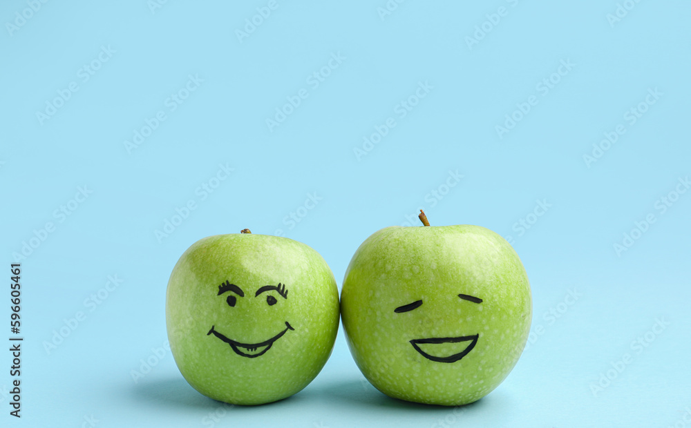 Apples with happy faces on blue background. Friendship Day celebration