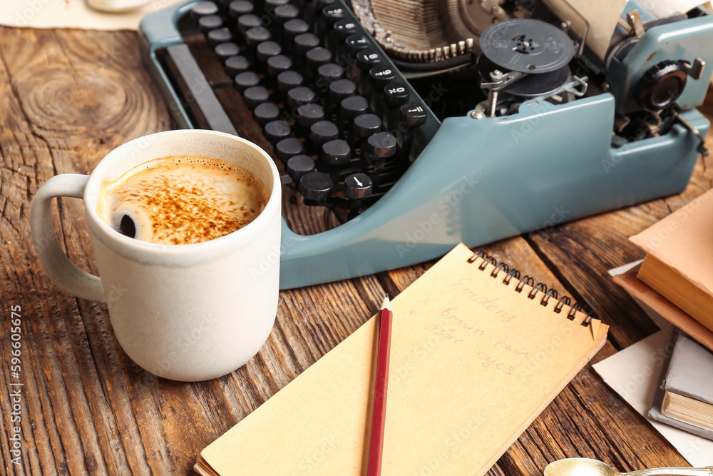 Cup of coffee with notebook and typewriter on wooden table, closeup