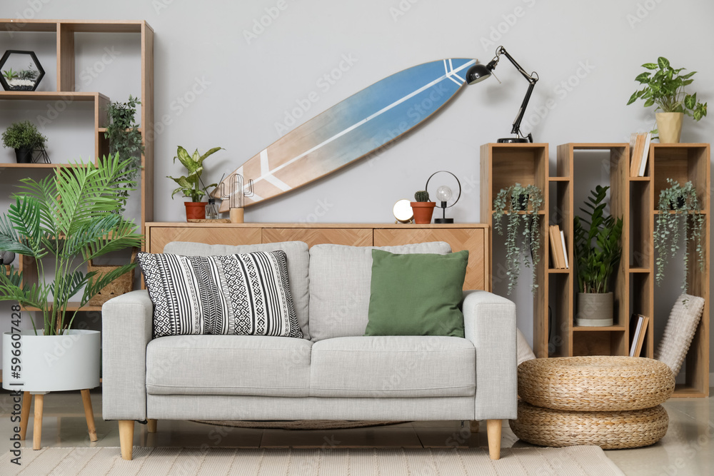 Interior of light living room with surfboard, shelving units and sofa