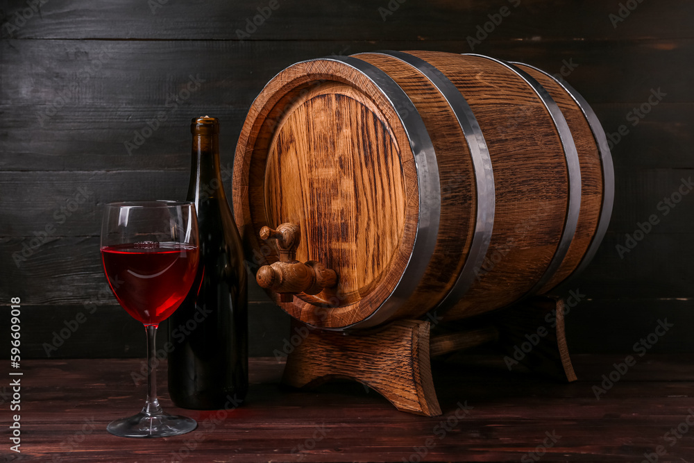 Oak barrel with bottle and glass of wine on dark wooden background