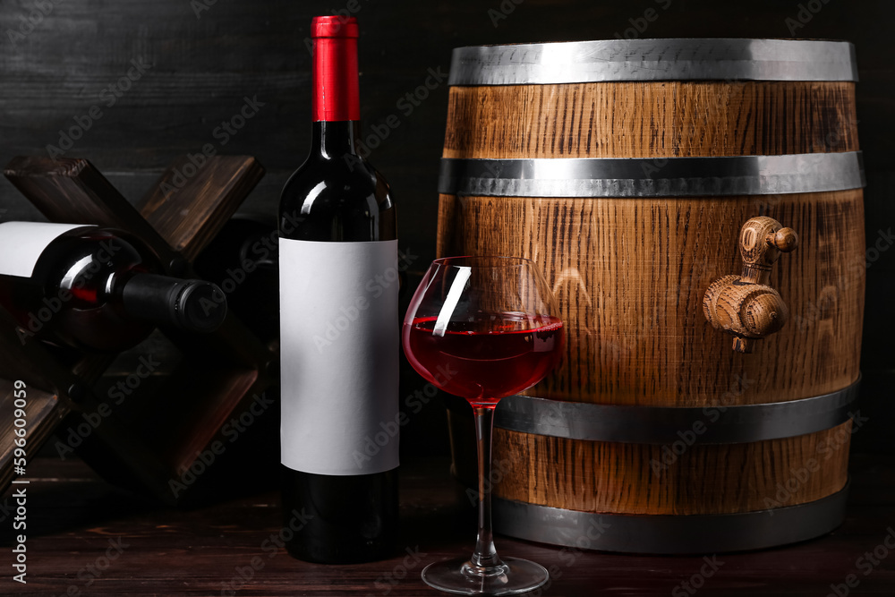 Oak barrel with bottle and glass of wine on dark wooden background