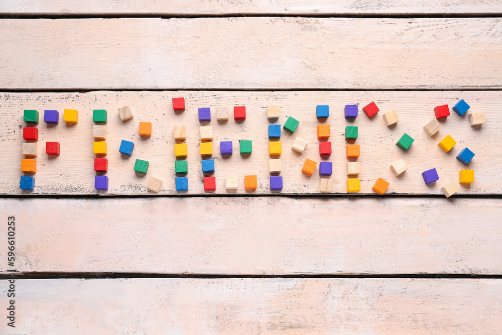 Word FRIENDS made of colorful cubes on white wooden background. Friendship Day celebration