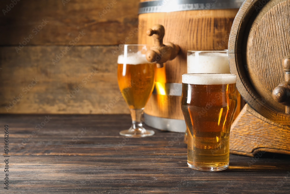 Oak barrels and glasses of cold beer on wooden background