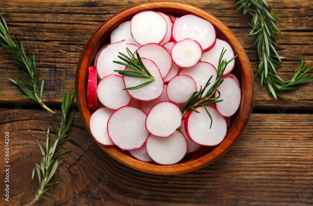 Bowl with slices of fresh radish and rosemary on wooden table