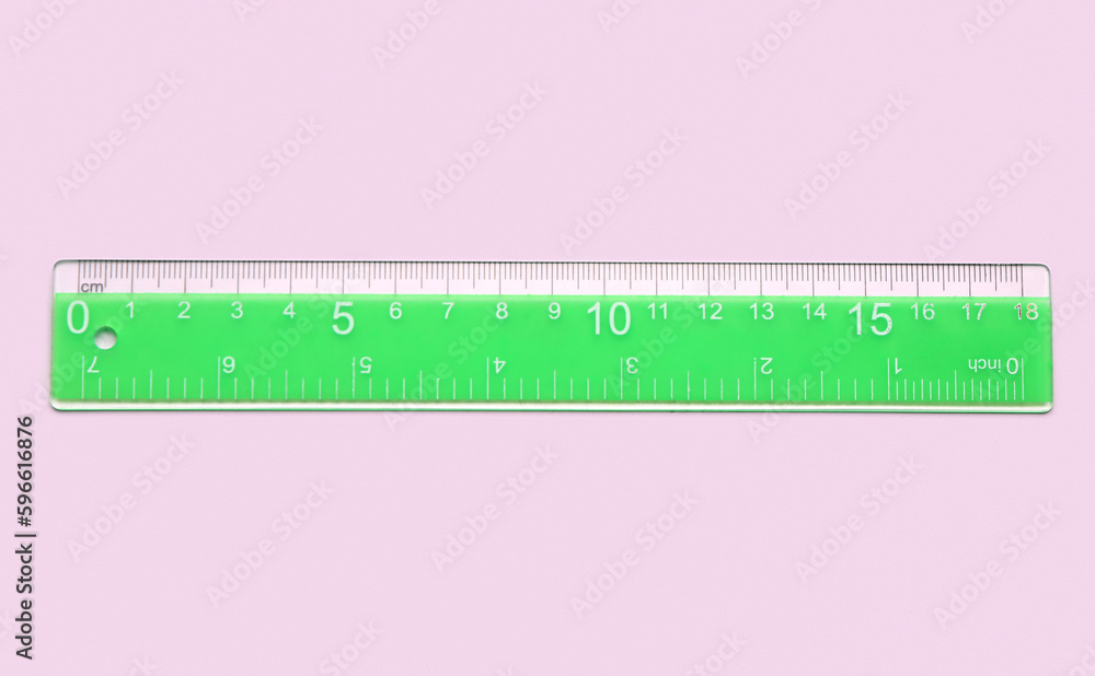 Green plastic ruler on pink background