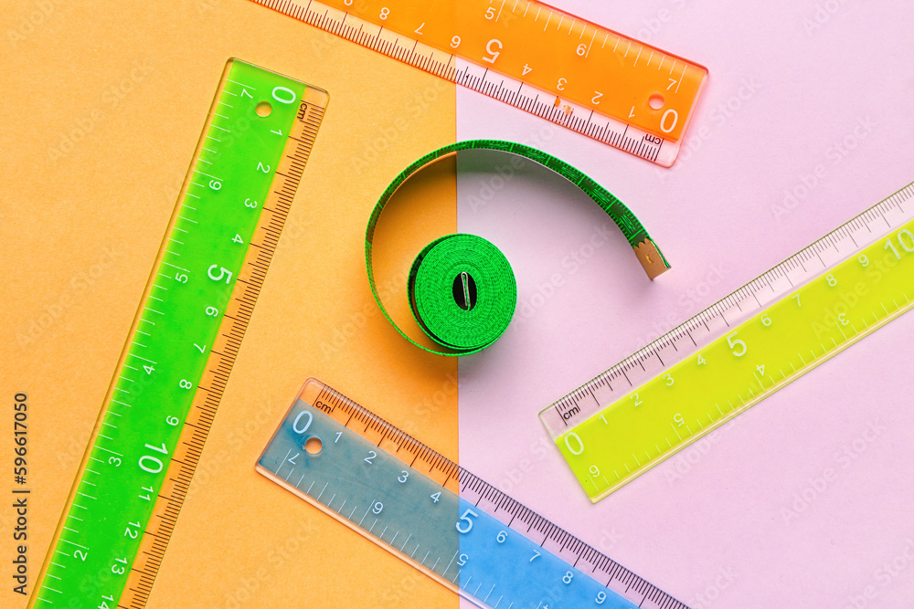 Colorful plastic rulers and measuring tape on color background