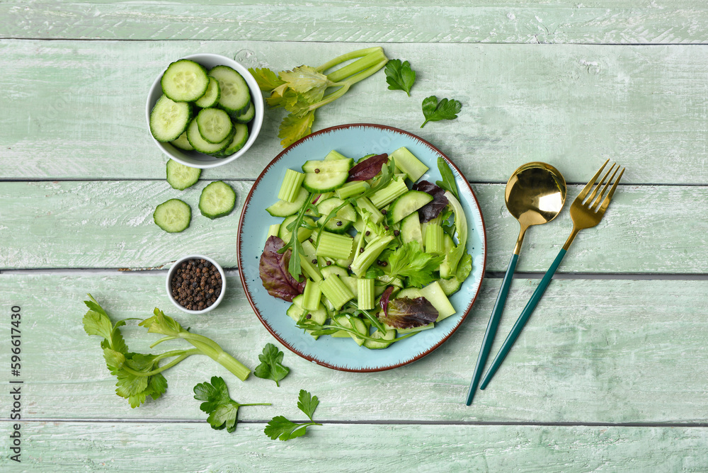 Plate with fresh salad and ingredients on green wooden background