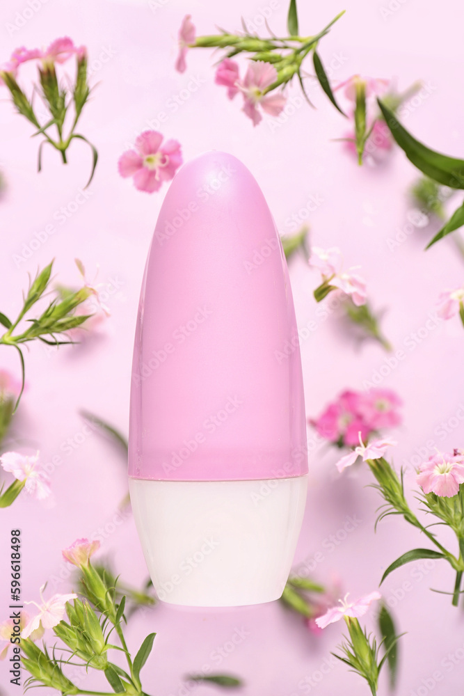 Deodorant bottle and flowers on pink background