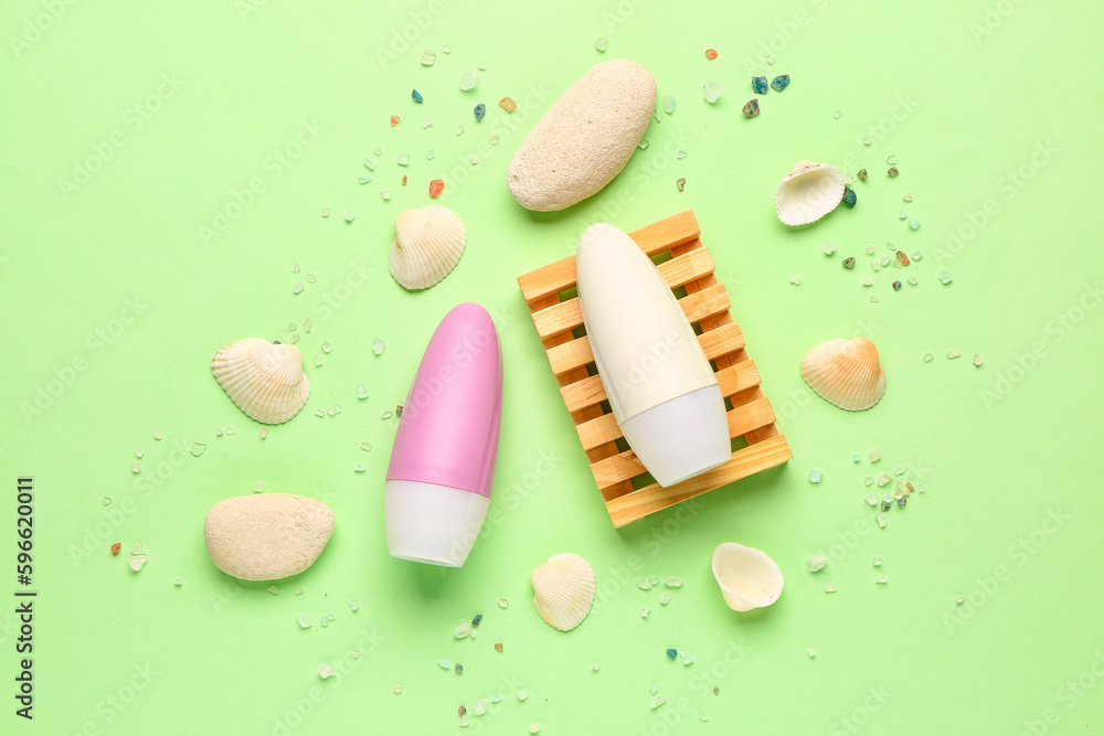 Deodorants with shells, stones and sea salt on light green background