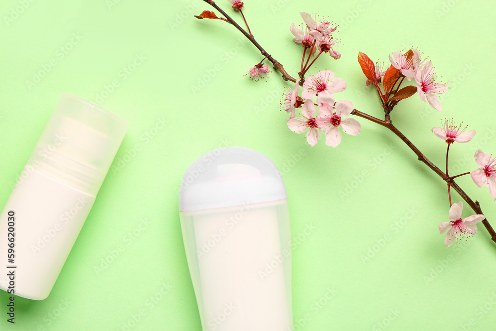 Deodorants with blooming branch on light green background