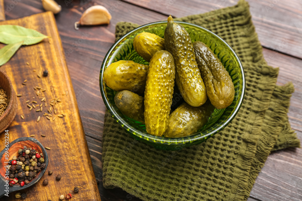 Bowl with tasty fermented cucumbers on wooden background