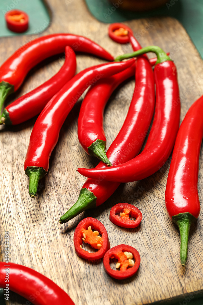 Wooden board with fresh chili peppers on table, closeup