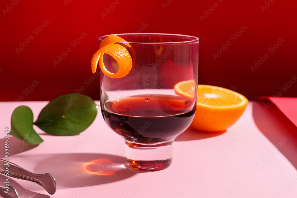 Glass of rum with orange on pink and red background