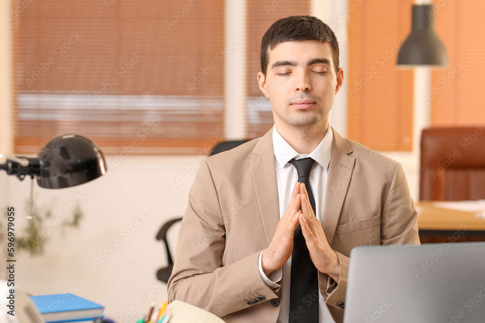 Young businessman meditating in office. Balance concept