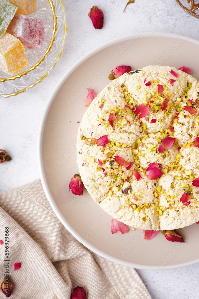 Plate of tasty Tahini halva with pistachios on light background, closeup