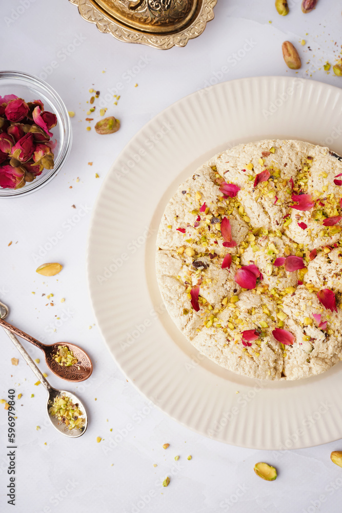 Plate of tasty Tahini halva with pistachios on light background, closeup