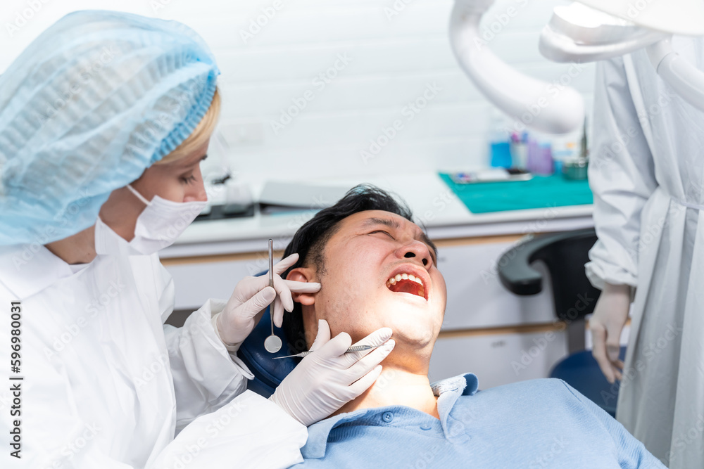 Caucasian dentist examine tooth for young man patient at dental clinic. 