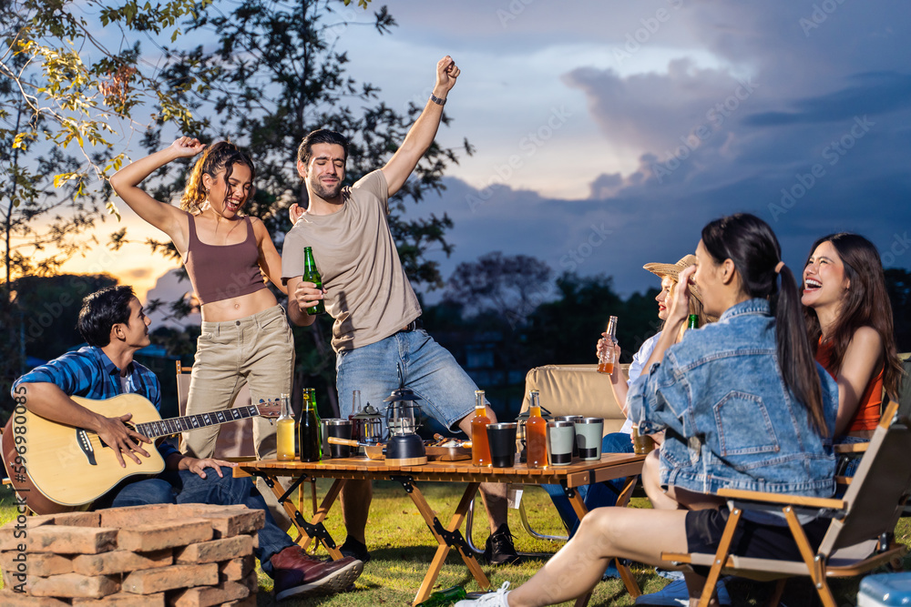 Group of diverse friend having outdoors camping party together in tent. 