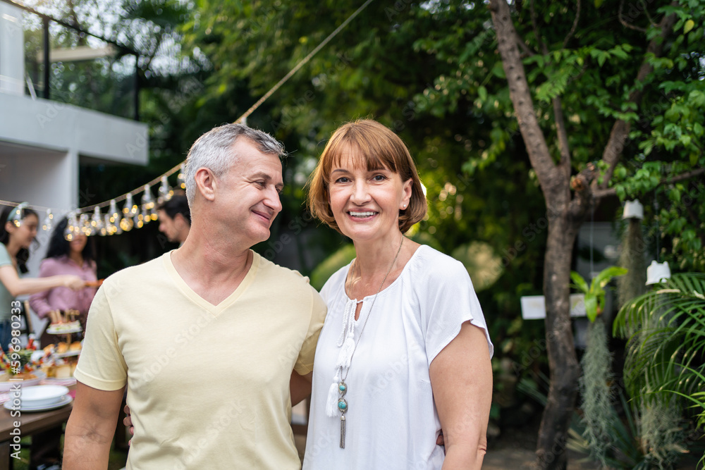 Portrait of senior couple looking at camera while having party outdoor. 