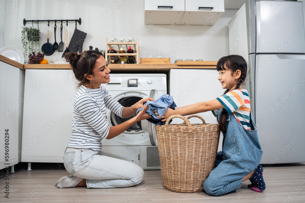 Caucasian beautiful mother teaching young daughter wash dirty clothes. 