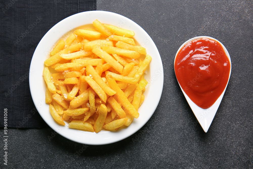 Plate with tasty french fries and ketchup on dark background