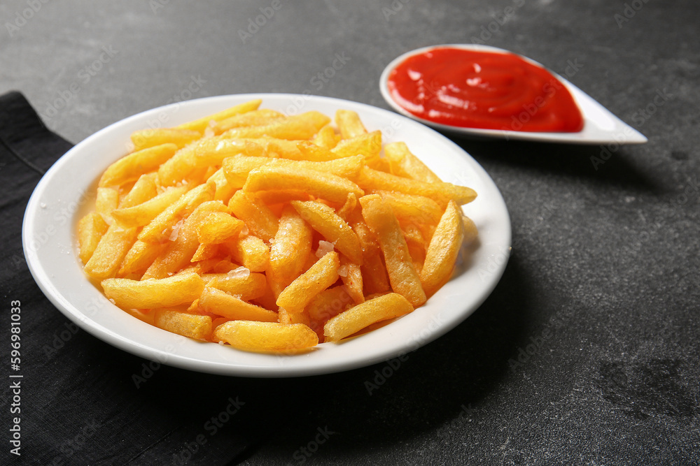 Plate with tasty french fries and ketchup on dark background, closeup