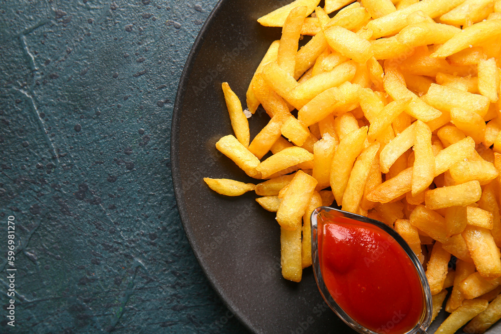 Plate with tasty french fries and ketchup on dark color background, closeup