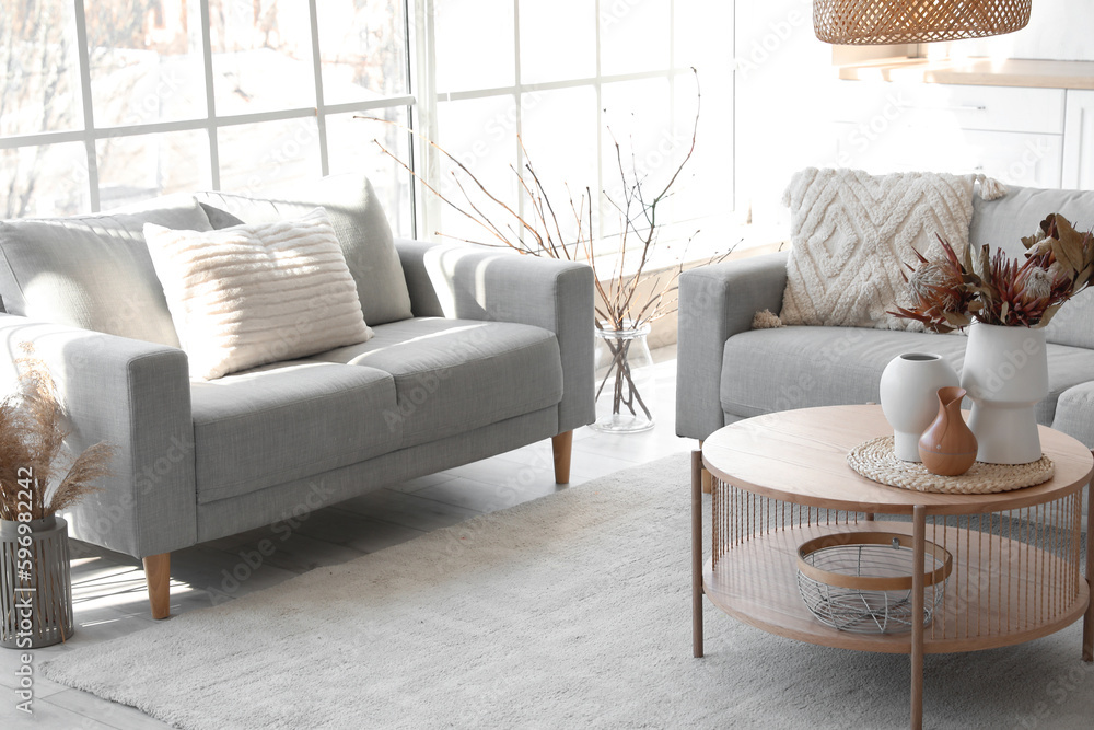 Cozy grey sofas and coffee table with bouquet of dried protea flowers in living room