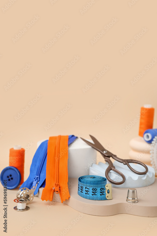 Podiums with tailors supplies on beige background