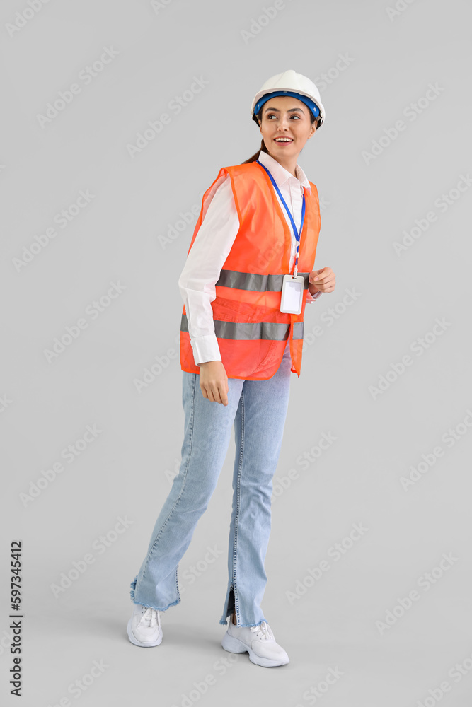 Female worker in vest on light background