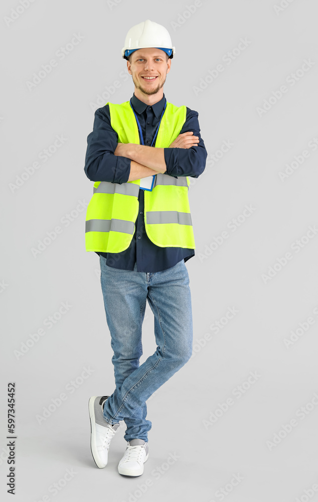 Male worker in vest and hardhat on grey background