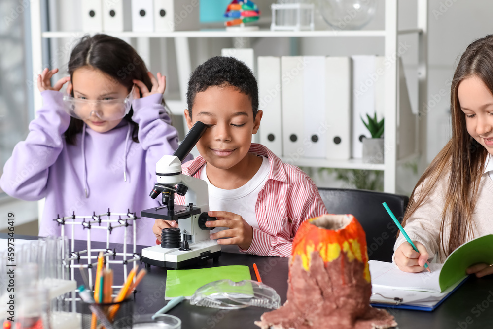 Little children with microscope studying chemistry in science classroom