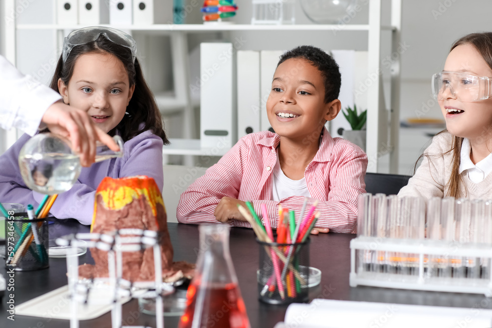 Little children having experiment with teacher and chemical volcano in science classroom