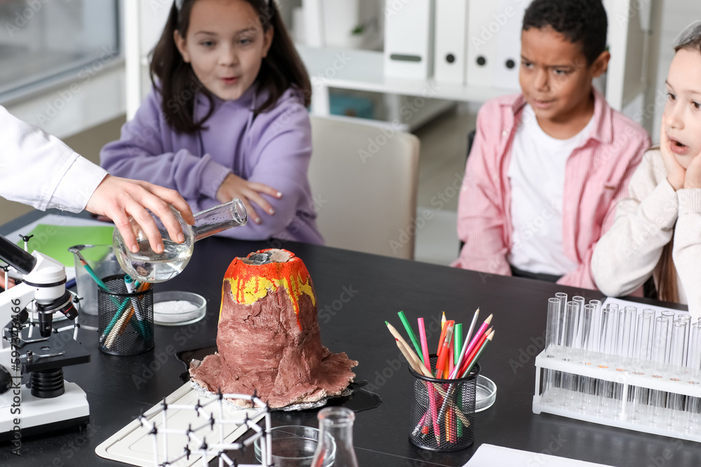 Teacher making experiment with chemical volcano for little children in science classroom