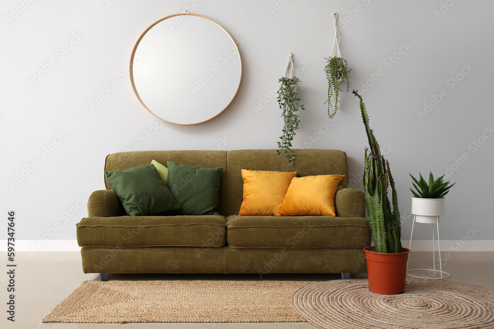 Interior of modern living room with cozy sofa, big cactus and houseplants